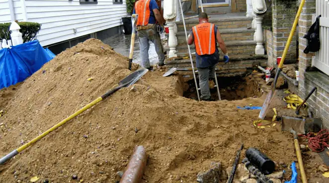 Contractors performing foundation protection and exterior drainage excavation near residential home steps in Tempe, AZ