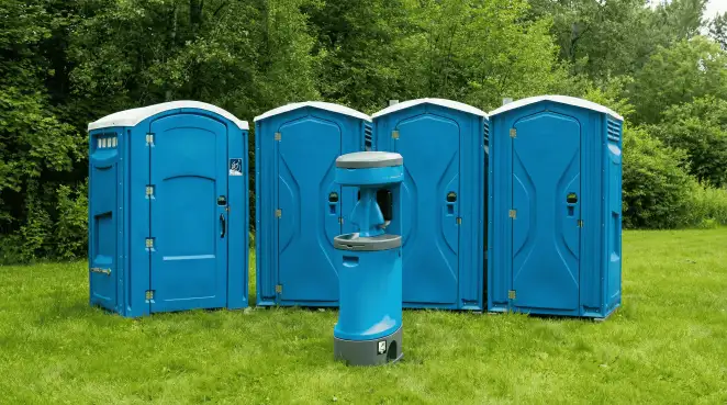 Four blue portable toilets and a matching hand washing station on grass near trees, a common sight at local outdoor events in Tempe, AZ
