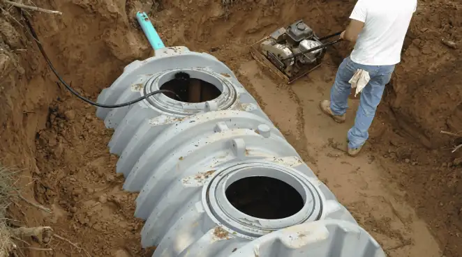 Septic tank installation showing a technician compacting soil around a new poly septic tank in an excavation pit in Tempe, AZ